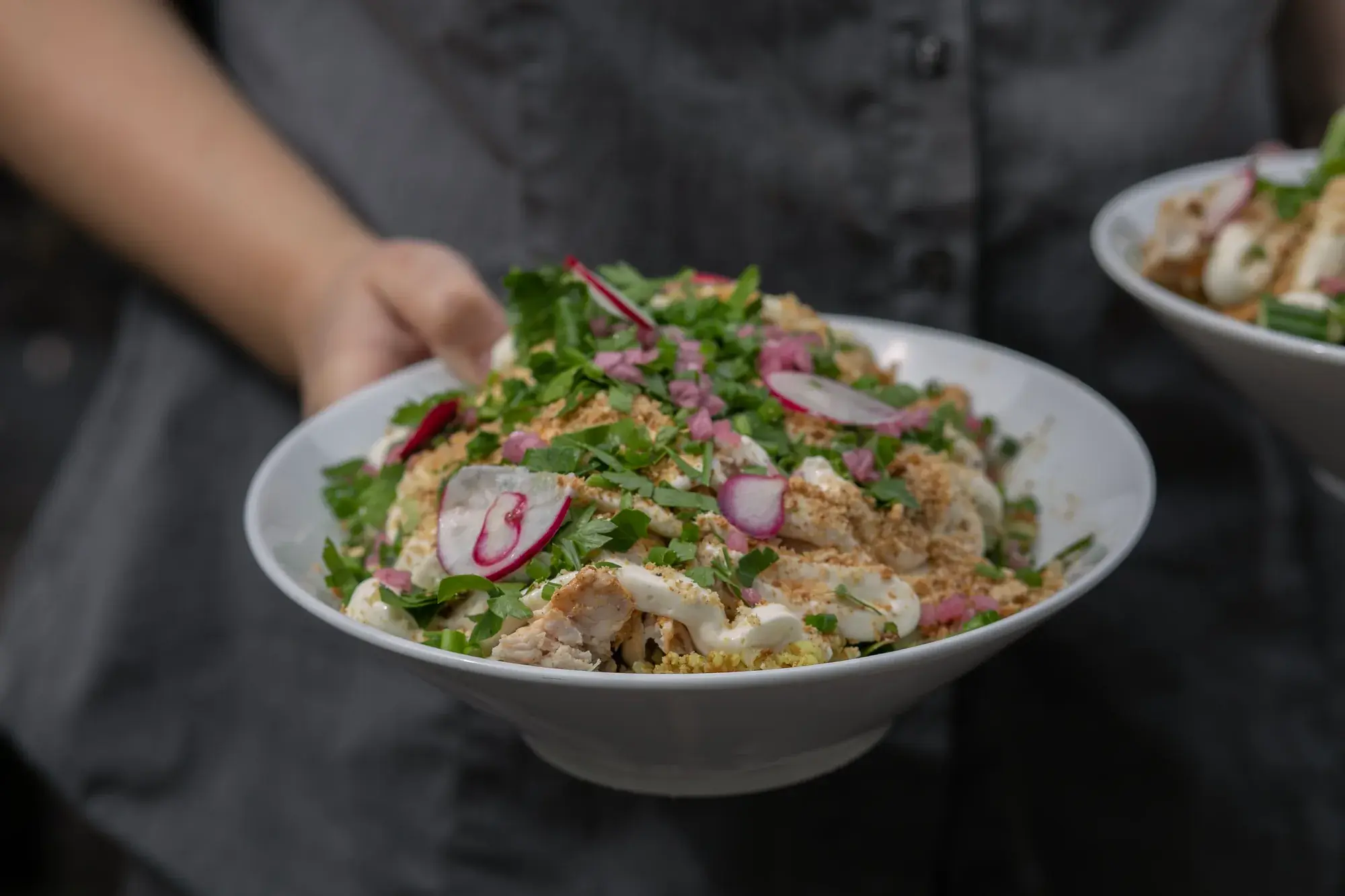 En sallad med gröna blad och rädisor serveras i en skål